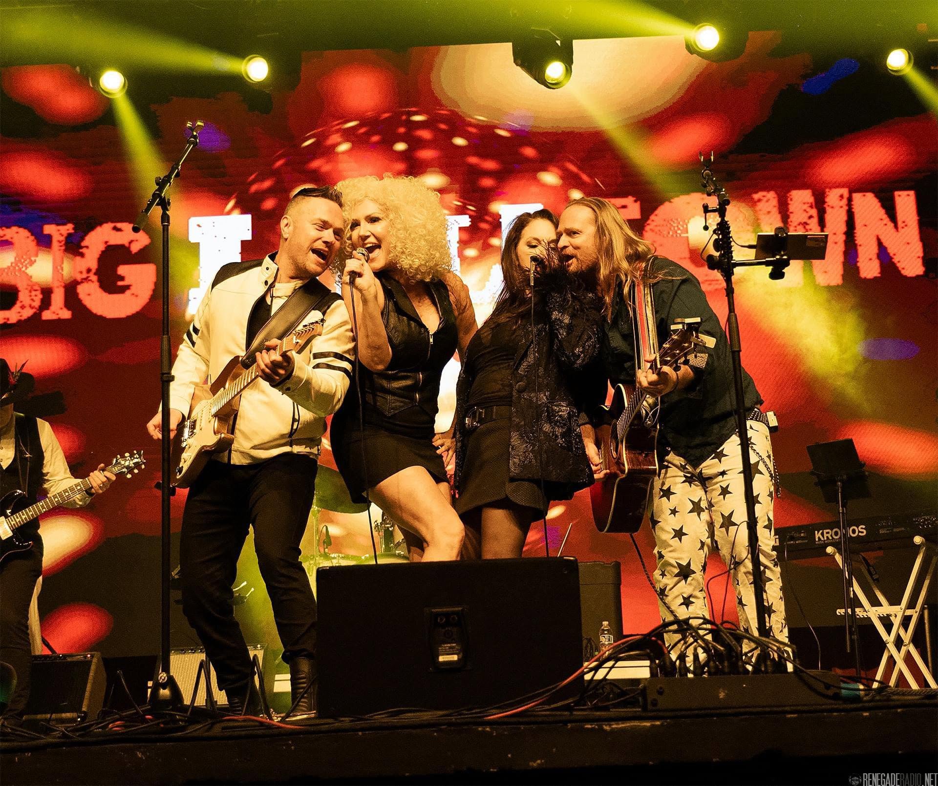 Big Little Town performers singing together on stage under bright lights.