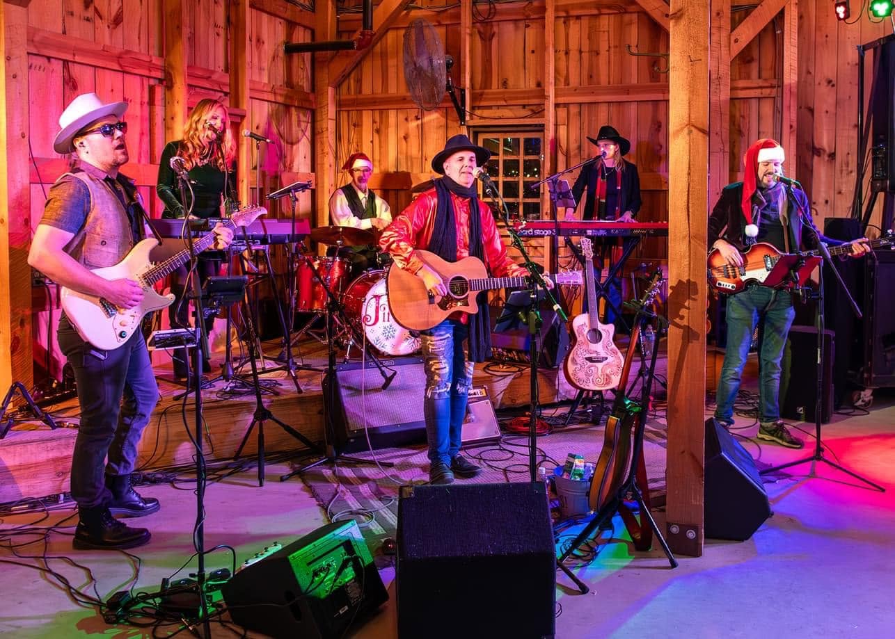Jingle! The Christmas Band performing together on a decorated barn stage.