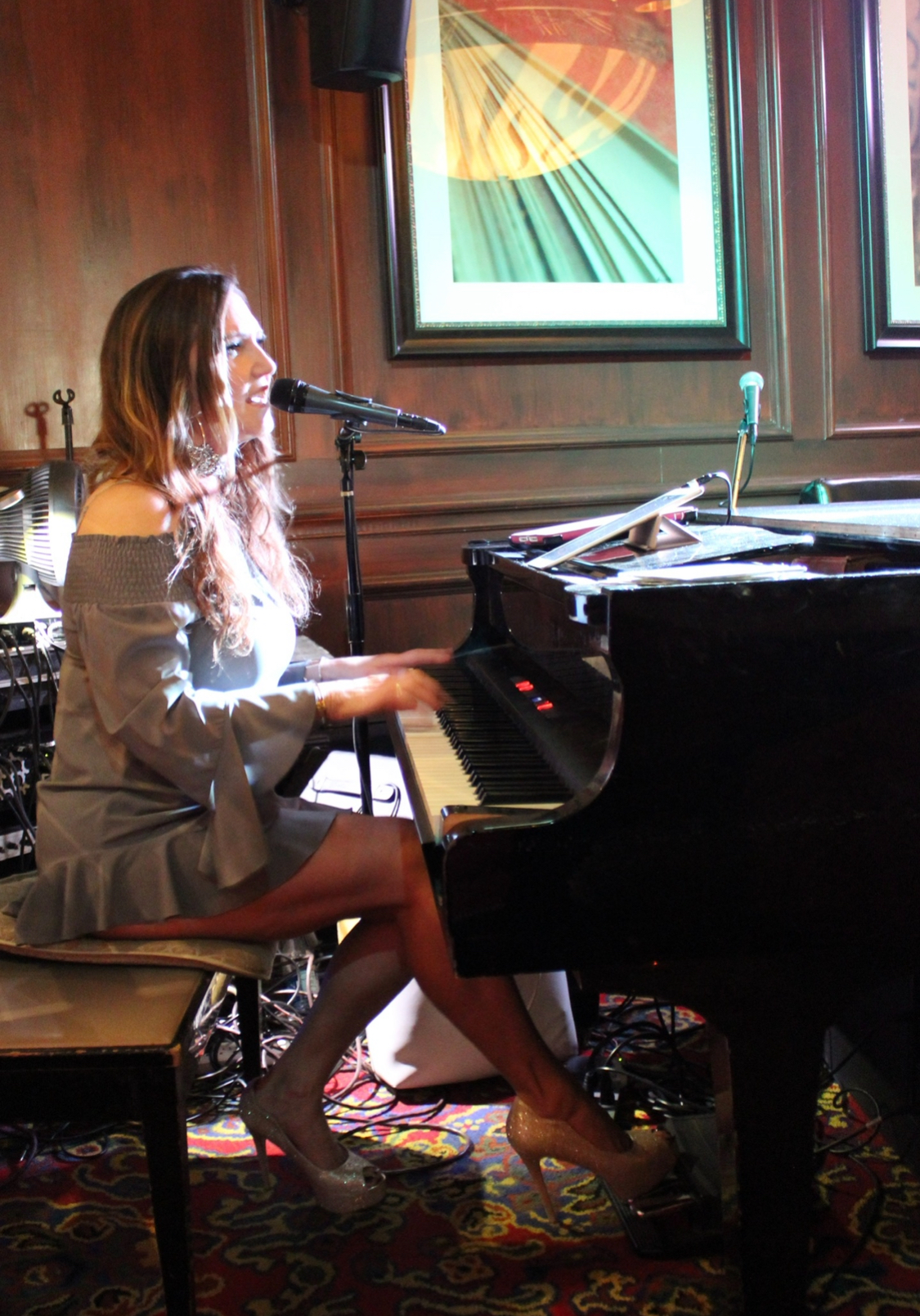 Dālene Richelle singing and playing grand piano in a silver dress.